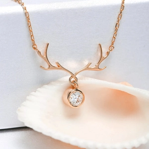 Macro shot of rose gold reindeer antler pendant necklace with round zircon on white shell