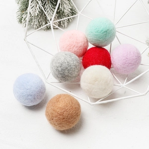 Colorful handmade wool felt balls in a white iron basket for Christmas DIY decorations