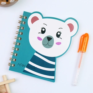 Close-up of mini coil notebook with blue polar bear cover and matching pen