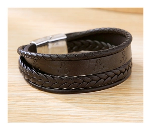 Détail du bracelet en cuir tressé marron foncé avec fermoir magnétique sur surface en bois