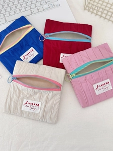Contrast zipper pleated nylon makeup pouch shown in four colors on a white workspace