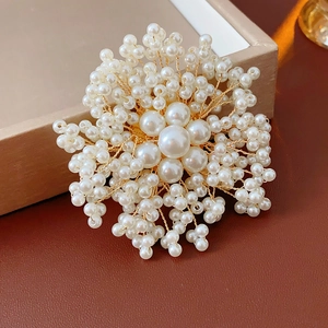 Close-up of handmade pearl flower brooch with intricate gold wire wrap and white beads