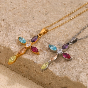 Detail of gold and silver cross necklaces with colorful gemstones on a stone surface
