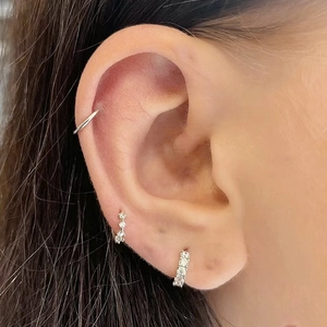 Macro shot of S925 sterling silver heart earrings and cubic zirconia ear cuff on ear