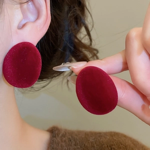 Gros plan sur des boucles d'oreilles ovales en velours rouge montrant la texture douce