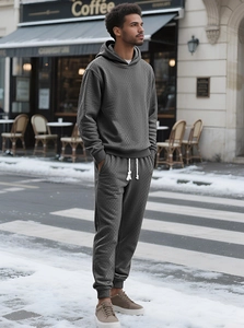 Detail of deep grey men's hoodie set with unique diamond knit texture in a street setting
