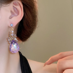 Macro shot of elegant purple teardrop crystal earrings with gold palace style setting