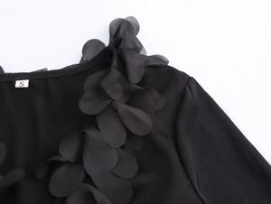 Detail of elegant V-neck blouse featuring 3D layered black petal floral decorations