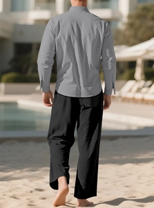 Men's linen set featuring grey long sleeve shirt and black trousers on a sunny beach