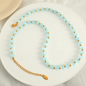 Elegant gold titanium steel necklace with blue cat eye stone beads on a tray