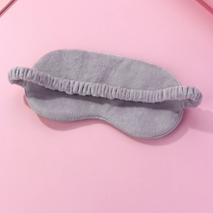 Plush cartoon sleeping eye mask in gray on pink background for fatigue relief and travel
