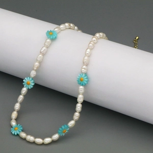 Detailed macro of natural white pearl necklace with blue daisy charms and golden clasp