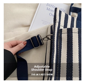 Detail view of the adjustable navy blue fabric shoulder strap on a striped canvas tote bag