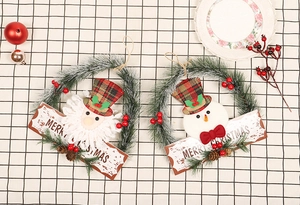 Detailaufnahme von Merry Christmas Holzschildern auf Kränzen mit Weihnachtsmann und Schneemann