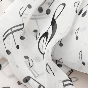 Macro view of lightweight white chiffon scarf with black musical note print details