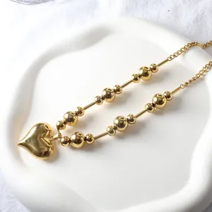 Detail of 18k gold plated heart pendant necklace with polished beads and tubular chain links