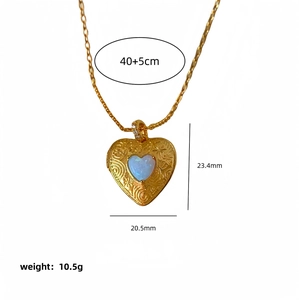 Gold-plated heart locket necklace with floral relief and opal stone on white background