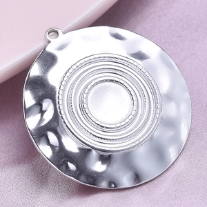 Detailed view of 304 stainless steel round pendant with hammered texture on pink fabric