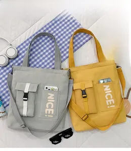Flat lay of gray and yellow canvas tote bags with buckles and nice lettering print