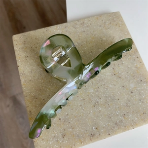 Detail of green textured acetate hair claw clip with iridescent finish on stone plate