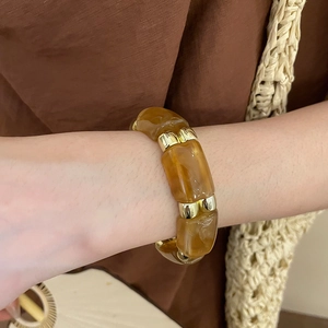 Detail of amber acrylic and gold cylinder beads on a stylish retro beaded bracelet