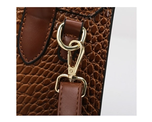 Macro detail of brown crocodile embossed leather and polished gold metal buckle hook