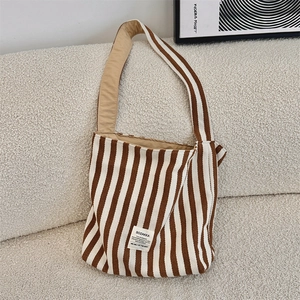Dettaglio borsa shopper in tela a righe con etichetta su sfondo divano beige neutro