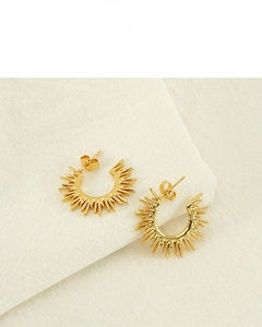 Detail of 18K gold plated sunflower C-shaped earrings on a cream fabric backdrop