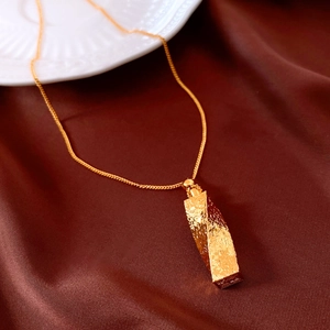 Detail shot of 24k gold plated twisted pendant with hammered texture on silk fabric