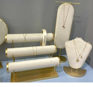 Close-up of golden necklaces and velvet headband on display stands in a retail setting