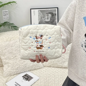 Detail of cream quilted makeup bag with dachshund embroidery and heart pattern