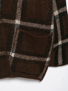 Macro view of thick knit plaid cardigan featuring deep brown tartan and stitched pocket