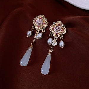 Detailed macro of vintage floral earrings with pink gems and white teardrop pendants