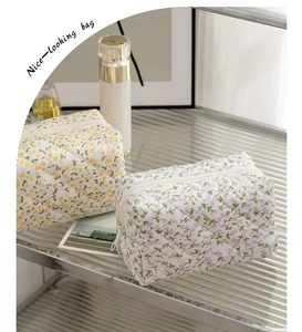 Floral quilted cosmetic bags displayed on a textured glass shelf with elegant props