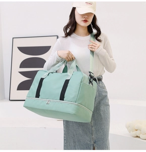 Detail of mint green waterproof travel bag showing double handles and bottom shoe compartment