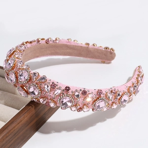 Detailed close-up of luxurious pink rhinestone headband on a wooden display stand