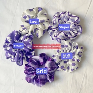 Set of five purple satin scrunchies featuring heart, floral, and plaid prints on white fabric