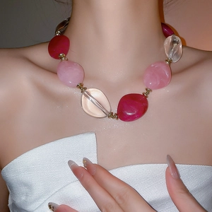 Detail shot of acrylic oval bead necklace with pink and deep red resin stones and gold spacers