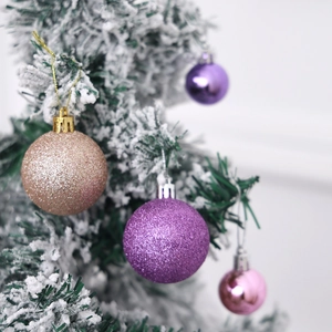Detailed view of champagne and purple glitter Christmas balls hanging on a flocked tree