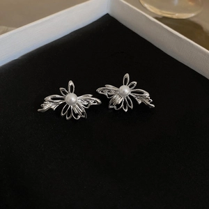 Detailed top view of silver bow earrings with white pearl on premium black velvet background