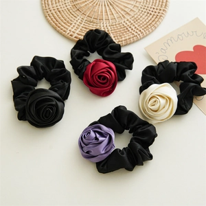 Detailed view of satin rose hair scrunchies in red, black, white, and purple colors