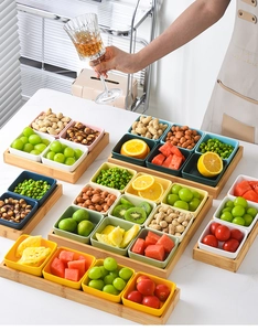 Colorful ceramic serving bowls with bamboo tray holding fresh fruits and nuts