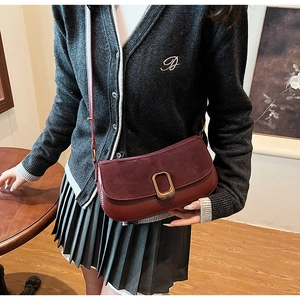 Detail of dark red vintage underarm bag with gold metal buckle and premium suede texture