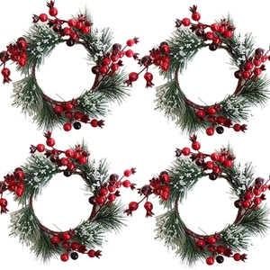 Set of four Christmas wreath candle rings with pine needles and red berries for decor
