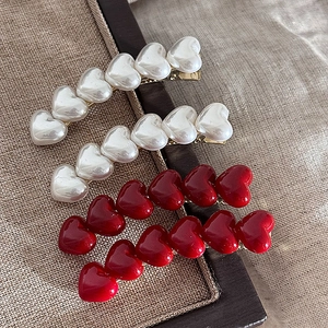 Detail of red and pearl white heart hair clips on a textured background