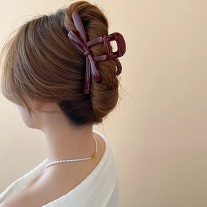 Detail showing the burgundy bow hair claw clip styled on brown hair for a refined look