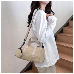 Detail showing khaki cylinder bucket bag with wide shoulder strap and round coin purse
