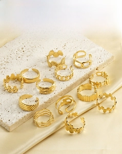 Close-up of assorted 18k gold plated stainless steel rings on silk and stone texture