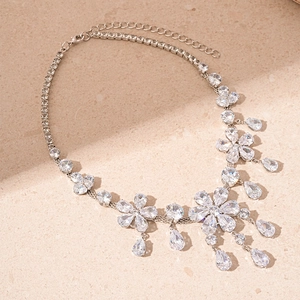 Detail of sparkling floral zircon necklace with elegant teardrop pendants on stone background