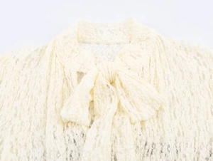 Close-up of cream white bubble lace texture and large bow tie on a summer jumpsuit